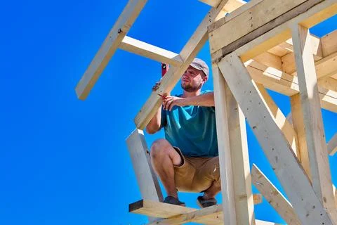 Rafters are positioned within timber framework, construction worker uses co.. Stock Photos