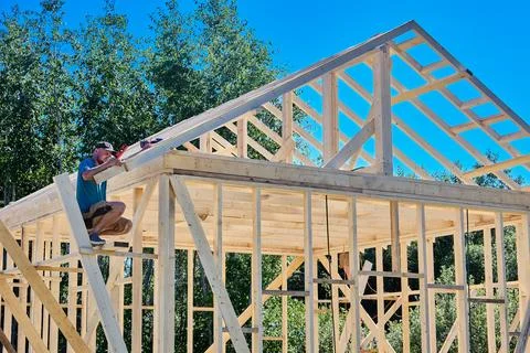 Rafters are secured within timber framework, construction worker uses compa.. Stock Photos