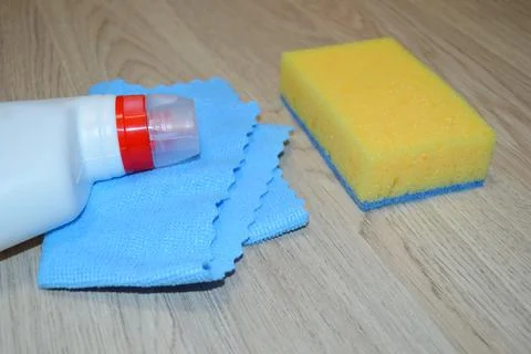 Rag, sponge and cleaning agent lie on a wooden floor. Cleaning service concep Foto stock