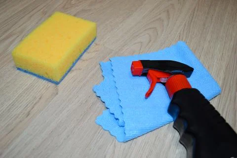 Rag, sponge and cleaning agent lie on a wooden floor. Cleaning service concep Stock Photos