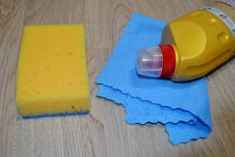 Rag, sponge and cleaning agent lie on a wooden floor. Cleaning service concep Stock Photos
