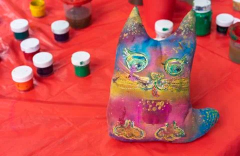 Rag toy cat painted with different colors. Soft toy cat on a red background. Stock Photos