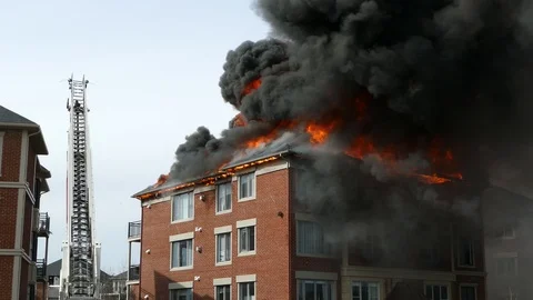 Raging flames and thick black smoke are produced by a major apartment fire Stock Footage 99009972