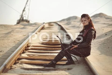 Raider girl in leather costume with a crossbow at post-apocalyptic world Stock Photos