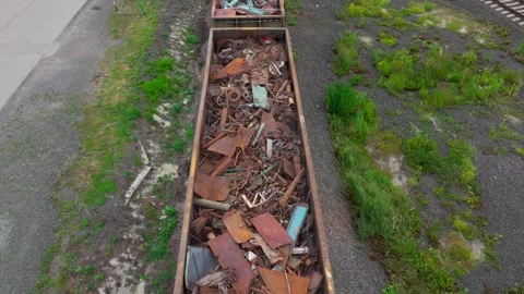 Rail wagons with scrap metal move by crossing while loaded long train departures Stock Footage 319953138