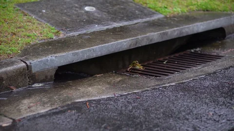 Rail water is running onto an asphalt into a gutter. Stockbeeldmateriaal 129746777