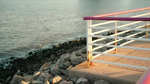 Railing, Riverside, Rocks, Waves, Sunset, Cinematic Color, 4K30p Stock Footage 305127958
