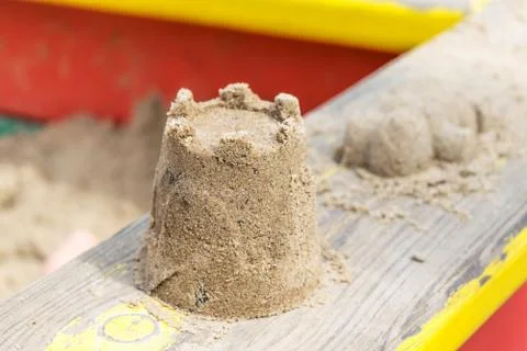 On the railing of the sandbox is a tower of sand. Stock Photos