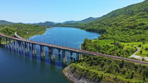 Railroad bridge crosses large river with green hills in the background during Stock Footage 342461675