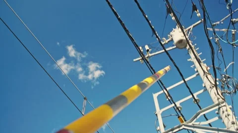 Railroad crossing gate arm lowering under blue sky Stock Footage 324875709