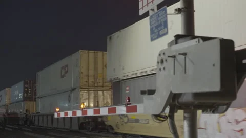 Railroad gate flashing in front of passing traincars Stock Footage 225498915