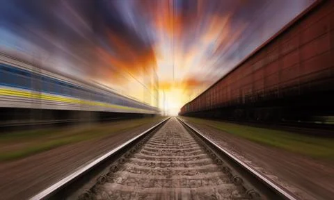 Railroad in motion at sunset with dramatic sky. Motion blur effect. Stock Photos