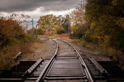 RAILROAD TRACKS IN MICHIGAN CURVE AROUND THE AUTUMN TREES UNDER A STORMY SKY Stock Photos