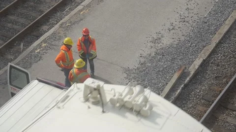 Railroad workers stand beside passing train Stock Footage 68999679