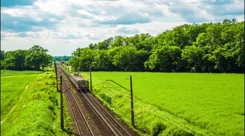 Railway across green fields, blue sky, two trains - time lapse Stock Footage 39040091