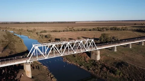Railway bridge over a small river, fields in the background Stock Footage