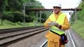 Railway employee in yellow uniform on railway line with tablet computer HD Footage