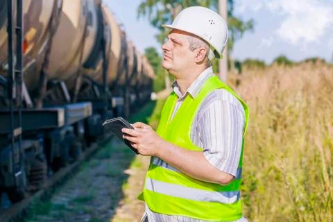 Railway Engineer using tablet PC on railway near freight wagons Stock Photos
