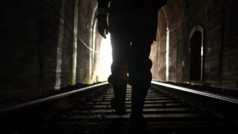 A railway engineer worker with a lantern in his hands walks through the tunnel Stock Footage 235217281