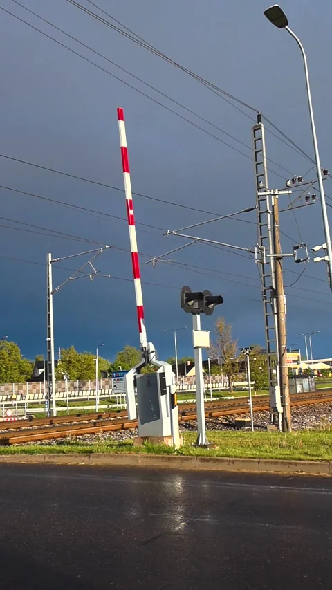Railway level crossing barrier opening with storm clouds in the background Stock Footage 340553948