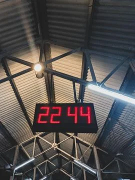 Railway platform digital clock under steel roof Stock Photos