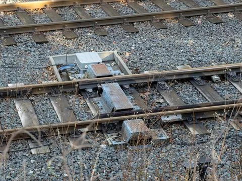 A railway switch point machine installed on wooden ties between steel tracks to Stock Photos
