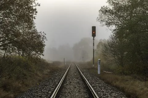 Railway track for engine unit passenger trains in autumn foggy morning Stock Photos