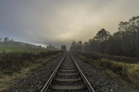 Railway track for engine unit passenger trains in autumn foggy morning Stock Photos