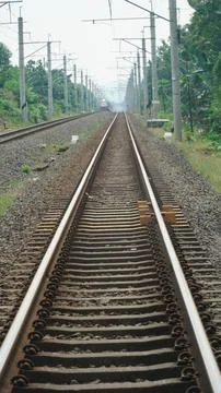 Railway Track Perspective with Distant Train and Electric Poles Stock Photos