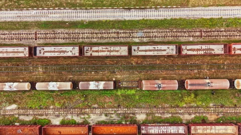 Railway tracks with cargo containers lined up near a grassy area during daylight Stock Footage 341587436