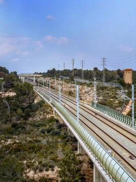 Railway tracks on elevated bridge through rugged landscape Фото