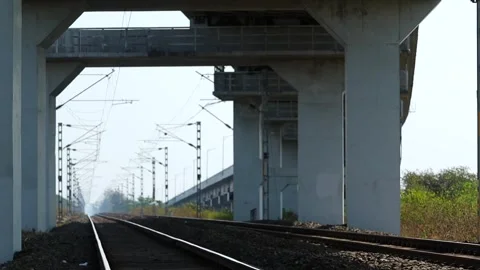 Railway tracks passing under large concrete bridge infrastructure in Assam Stock Footage 330706276