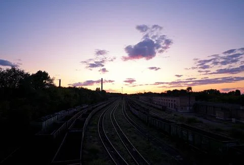 Railway tracks at sunset with freight wagons in industrial area Stock Photos
