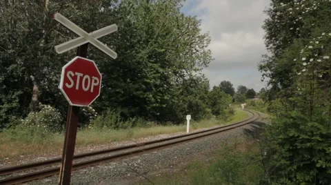 Railway train crossing path with stop sign in the foreground and clouds passing Stock Footage 52129112