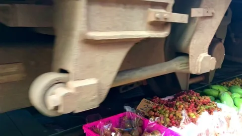 Railway train driving close to fruit and vegetable on ground in Maeklong Railway Stockbeeldmateriaal 125523391