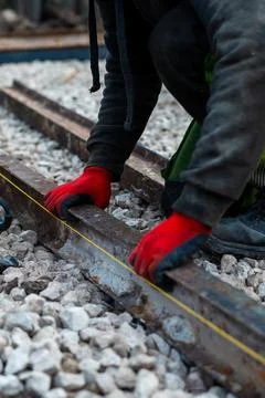 Railway worker aligns rusty rails with measuring line on ballast Fotos Stock