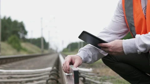 The railway worker checks the rails with a level and makes notes on the tablet. Stock Footage 214664985