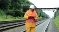 Railway worker in yellow uniform and white hard hat with documents in hands HD Footage