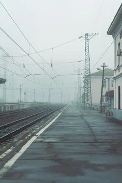 Railways station platform at cold cloudy mist or fog day, empty train station in Stock Photos