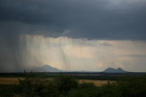 Rain on a background of mountains. Gray stripes of raindrops Stock Photos