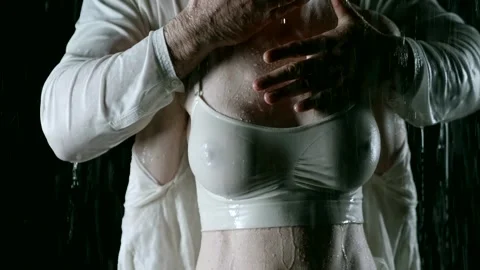 In the rain on a black background, a middle-aged couple, a man with a muscular Stock Footage 274727418