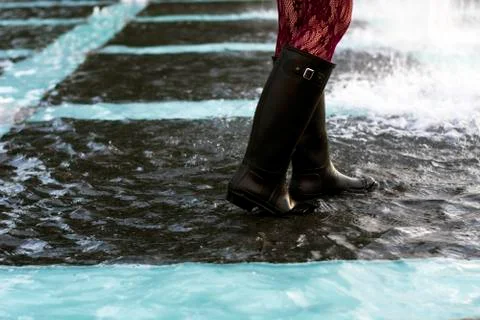 Rain boots splashing in a puddle Stock Photos