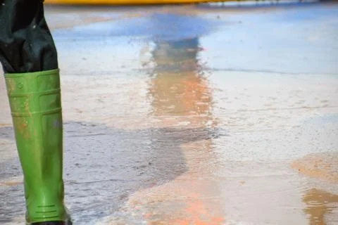 Rain boots of a worker cleaning mud from the ground after a flood Foto stock