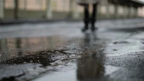 Rain in city, closeup of drops falling on asphalt, blurred silhouette of person 스톡 동영상 168709092