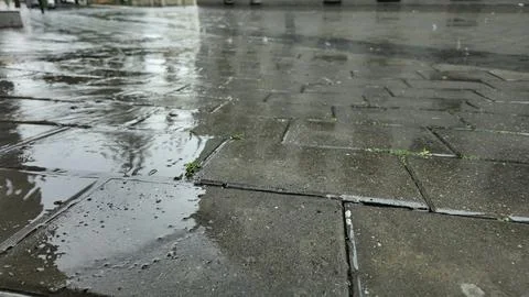 Rain in the city. View of raindrops falling on the pavement Raindrops falli.. Fotos de archivo