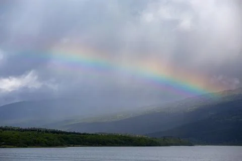 Rain cloud and rainbow over mountain lake, Shaori Reservoir Georgia Stock Photos