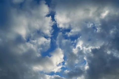 Rain clouds creep on both sides and cover the clear blue sky. Stock Photos