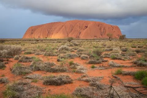 Rain clouds give a dramatic sky over Uluru Stock Photos