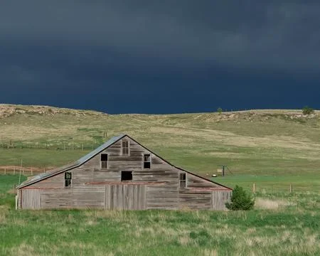Rain clouds loom over a weathered wooden barn Stock Photos