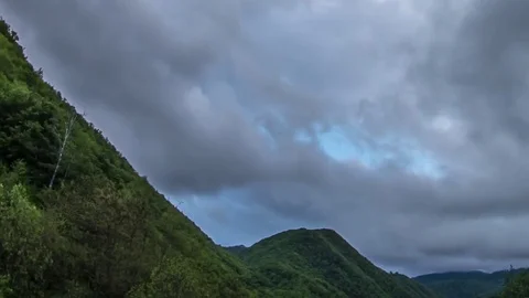 Rain clouds moving quickly over some wooded hillsides off a mountain v Video stock 69831727